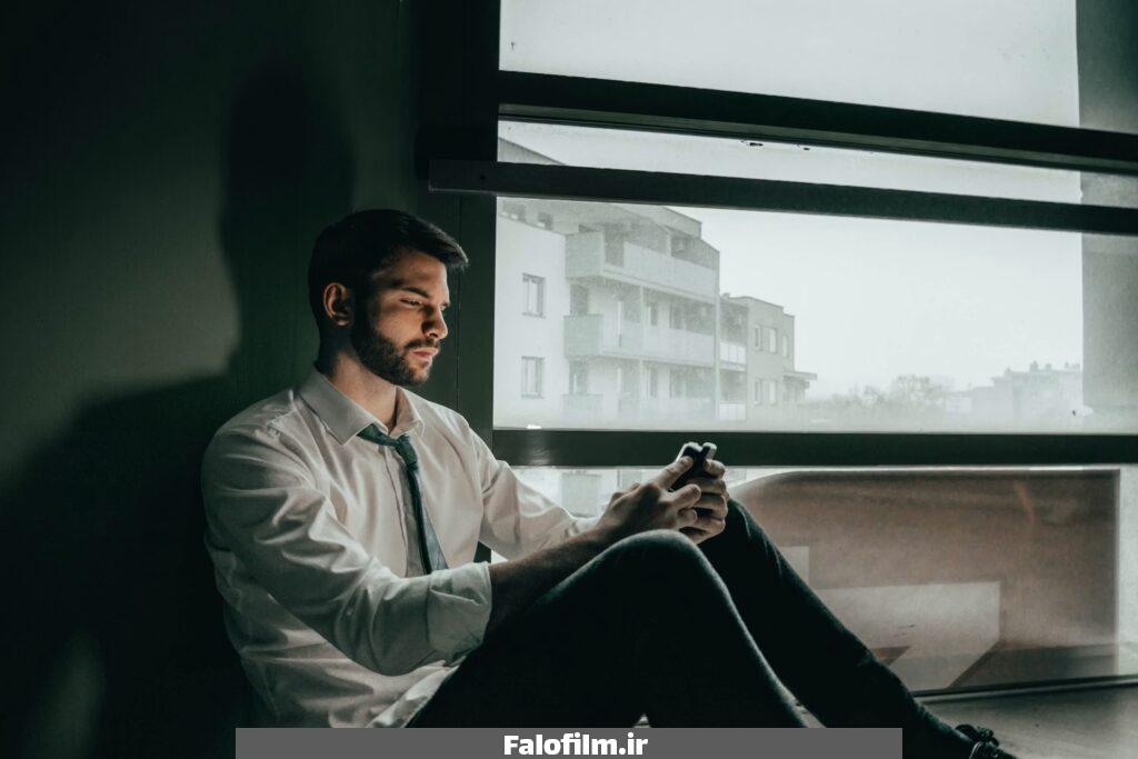 یک مرد ناراحت که به تلفن همراهش نگاه میکند